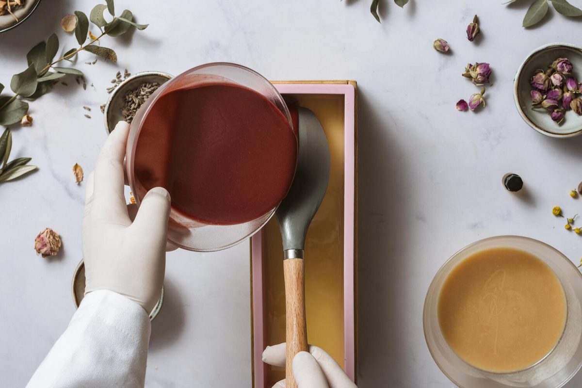 Beginner pouring cold process soap batter into a silicone mold